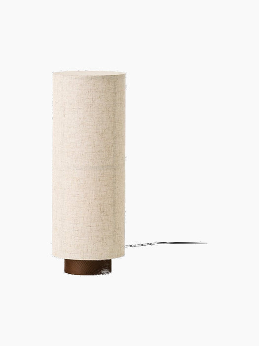 A front-on image of the Hashira Table Lamp in Raw. The lamp has a tall cylindrical linen shade on a dark stained ash base.