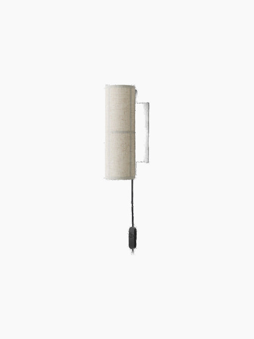 A Hashira Wall Lamp with a cylindrical, textured raw linen shade. It has a black wall mount and a black cord with a switch.