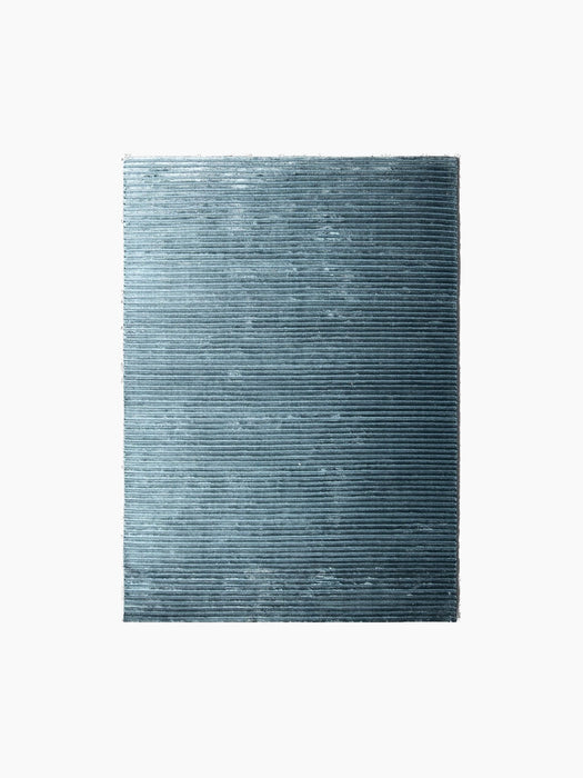 A rectangular swatch of the Houkime Rug in Midnight Blue, with finely ribbed, horizontal texture against a black background.