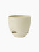 The Hydrous Planter in a pale, off-white Ashen finish. A rounded ceramic planter with a notch and matching saucer.