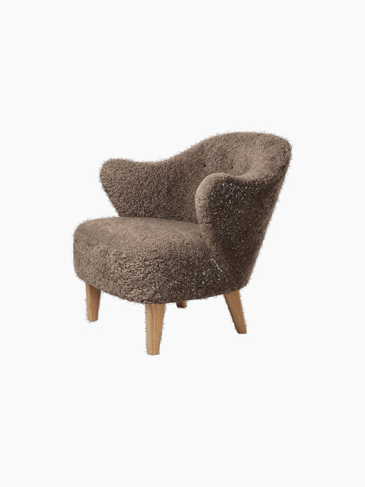 Angled view of the Ingeborg Lounge Chair in textured, brown Sahara sheepskin with light oak legs on a black background.