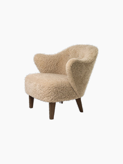 A three-quarter view of the Ingeborg Lounge Chair in textured honey sheepskin with sculptural arms and dark oak legs.