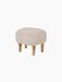 A three-quarter view of the Ingeborg Ottoman. The oval stool has a fluffy, off-white Sheepskin Moonlight seat and oak legs.