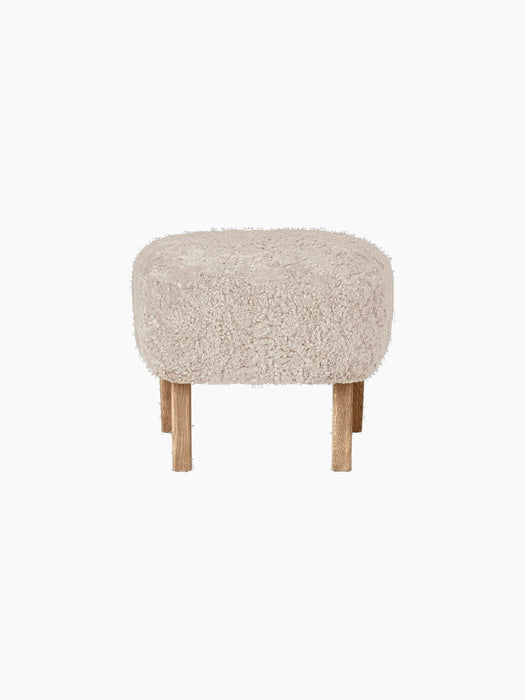 Front view of the Ingeborg Ottoman, upholstered in fluffy off-white Sheepskin Moonlight, with four short natural oak legs.