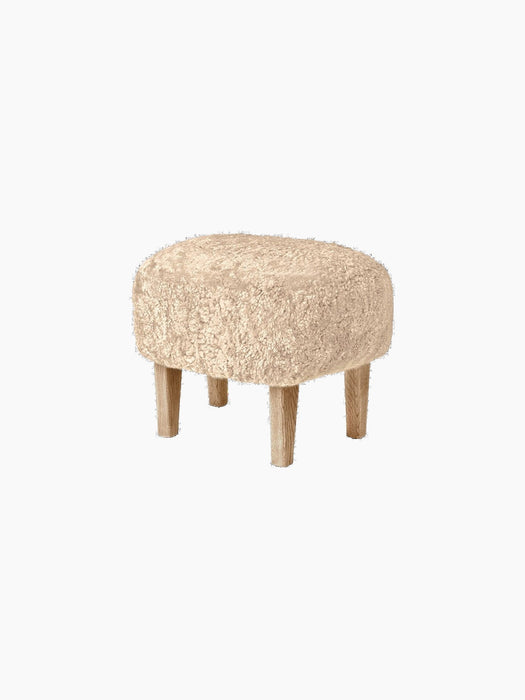 Ingeborg Ottoman, Sheepskin, shown from the side. The ottoman has a plush, honey sheepskin top and four natural oak legs.