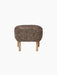 The oval Ingeborg Ottoman with a cushioned top upholstered in curly Sahara sheepskin on four short natural oak legs.