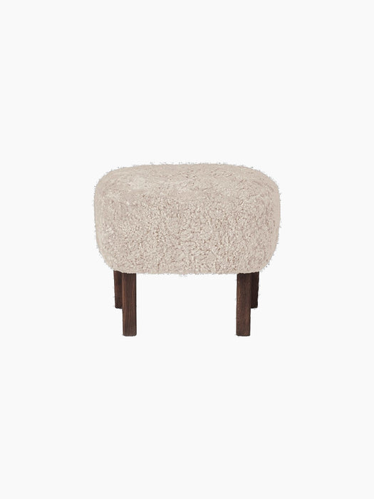 A front view of the Ingeborg Ottoman, upholstered in fluffy, off-white Moonlight sheepskin with four dark stained oak legs.