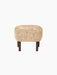 Side view of the Ingeborg Ottoman with a plush, honey-coloured sheepskin seat and short, dark-stained oak legs.