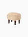 Ingeborg Ottoman with a round, honey-coloured sheepskin top and four short, dark-stained oak legs, on a black background.