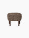 A studio shot of the Ingeborg Ottoman in Sahara sheepskin. The footstool has a textured, brownish top and four dark oak legs.