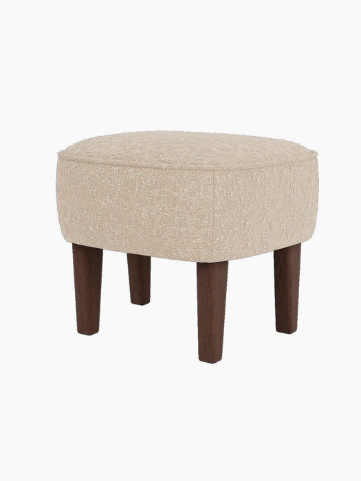 The Ingeborg Ottoman, shown from a three-quarter angle, with a textured light beige cushion and four tapered dark oak legs.