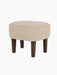 The Ingeborg Ottoman, shown from a three-quarter angle, with a textured light beige cushion and four tapered dark oak legs.