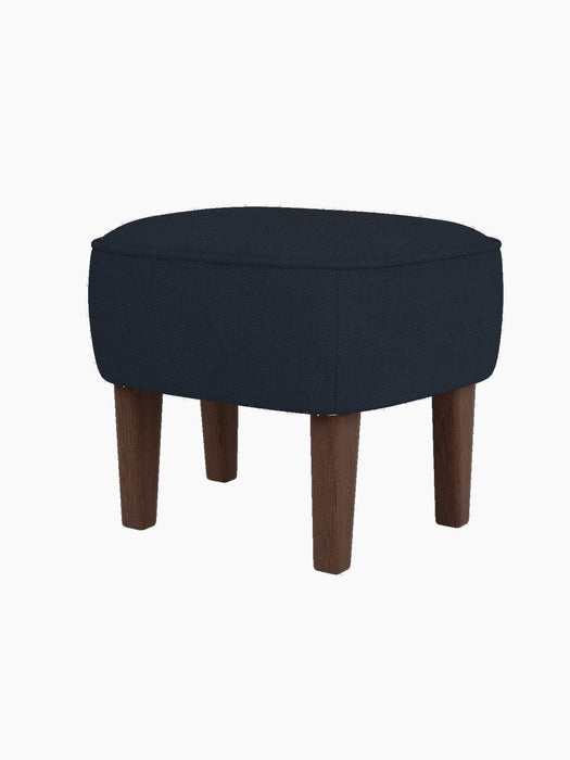 The Ingeborg Ottoman, upholstered in dark blue Fiord 782 fabric with smoked oak legs, shown against a plain black background.