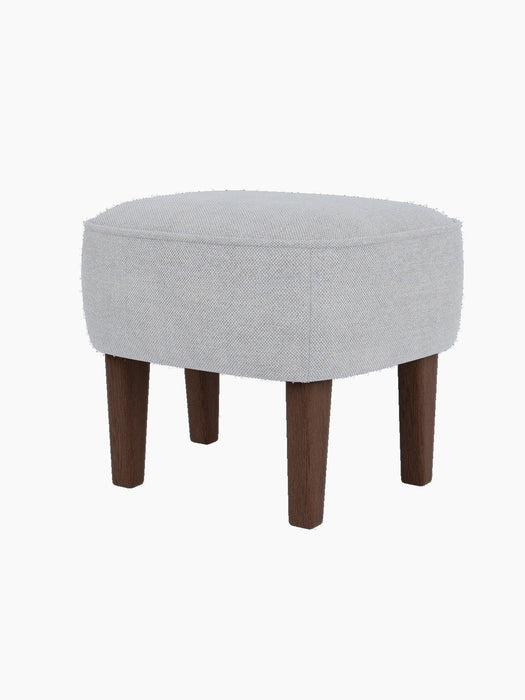The Ingeborg Ottoman in a light grey Fiord 751 textile, shown from a three-quarter angle with dark-stained smoked oak legs.