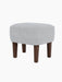 The Ingeborg Ottoman in a light grey Fiord 751 textile, shown from a three-quarter angle with dark-stained smoked oak legs.