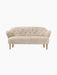 Front view of the Ingeborg Sofa in off-white Moonlight sheepskin, featuring a button-tufted back, flared arms, and oak legs.