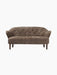 A front view of the Ingeborg Sofa in dark brown Sahara sheepskin, featuring a button-tufted back and dark stained oak legs.