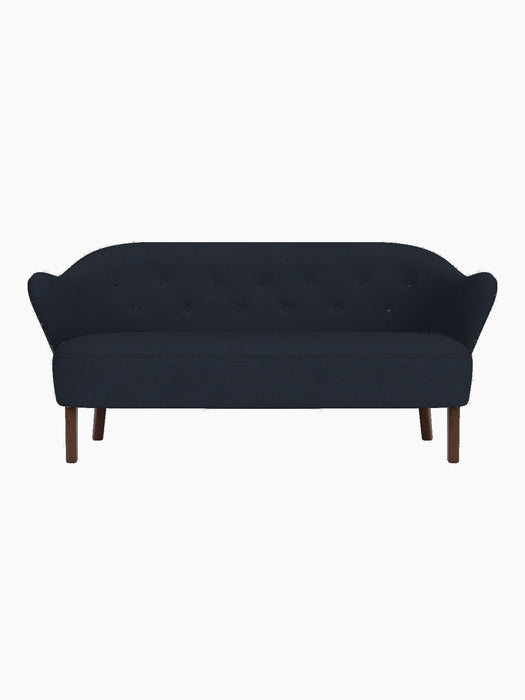 Front view of the Ingeborg Sofa in a dark navy blue textile, featuring a button-tufted back and smoked oak legs.