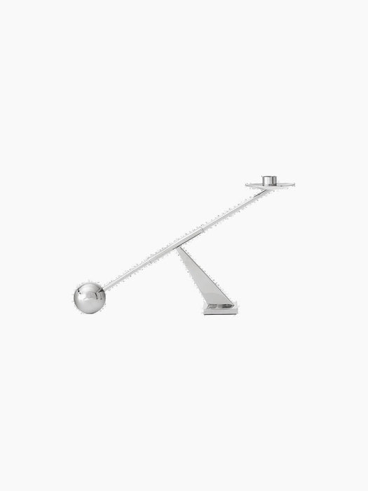 Side view of the sculptural Moment Candlestick Holder. Polished chrome holder balances like a see-saw on a triangular base.