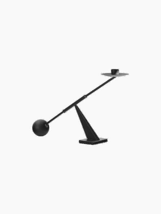 A sculptural Moment Candlestick Holder in black, from an angle, featuring a balancing arm with a spherical counterweight.