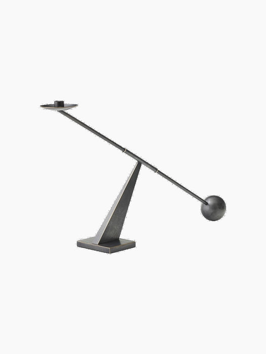 The Poem Candleholder in bronzed steel. A balanced rod with a candle socket and sphere rests on a triangular base.