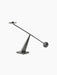 The Poem Candleholder in bronzed steel. A balanced rod with a candle socket and sphere rests on a triangular base.