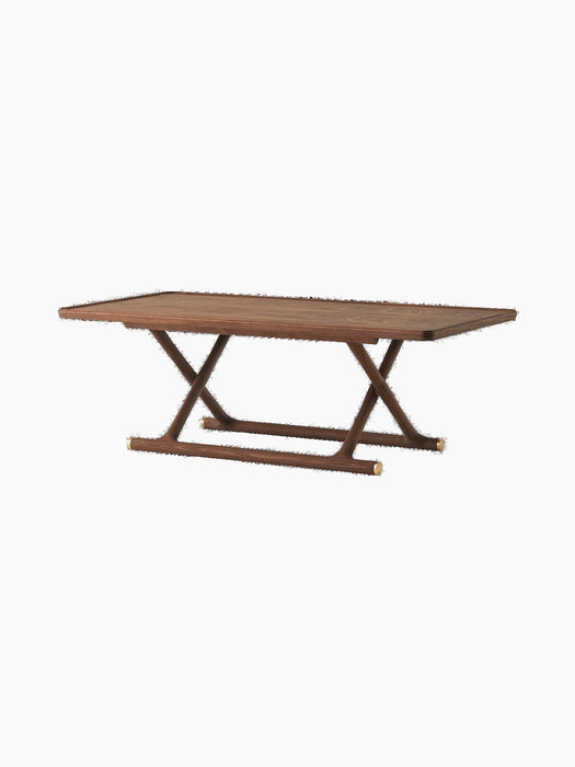 Jäger Lounge Table in oiled walnut shown at an angle, with a rectangular top and foldable X-shaped base with brass fittings.