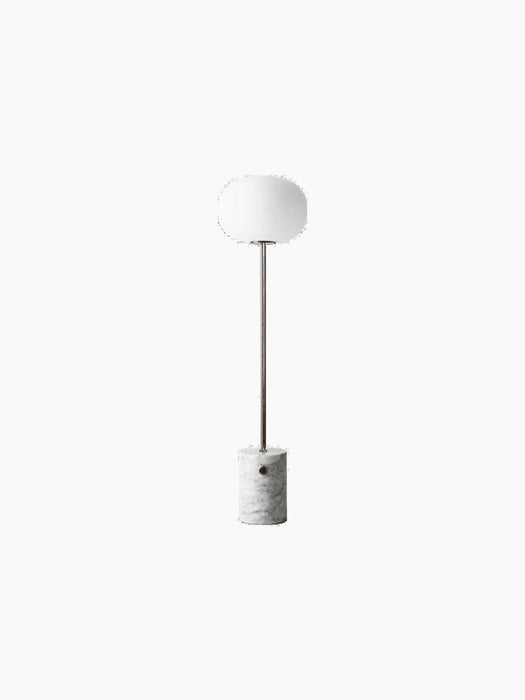 The JWDA Floor Lamp with a cylindrical white Carrara marble base, a bronzed brass stem, and an elliptical white glass shade.