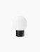 JWDA Table Lamp, Portable, in black, seen from the back. It features a solid black cylindrical base and a white glass shade.