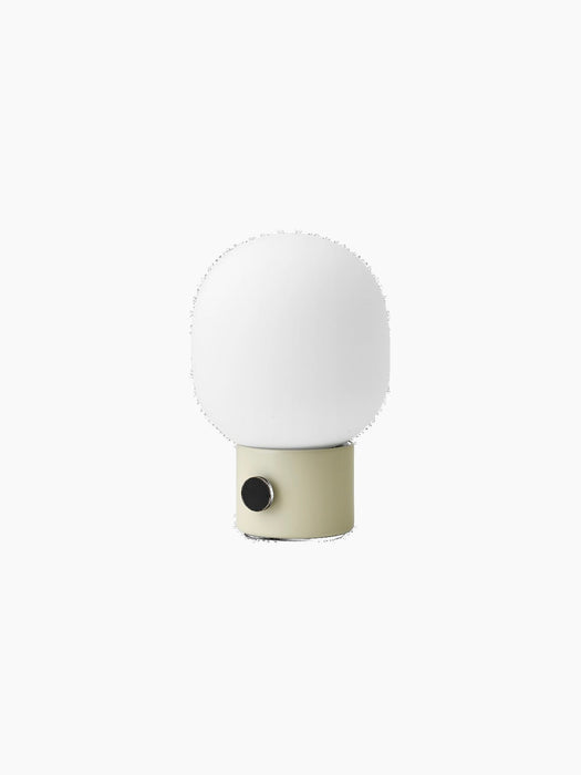 An angled view of the JWDA Portable Table Lamp in Alabaster White, with its cylindrical base, black dimmer and frosted shade.