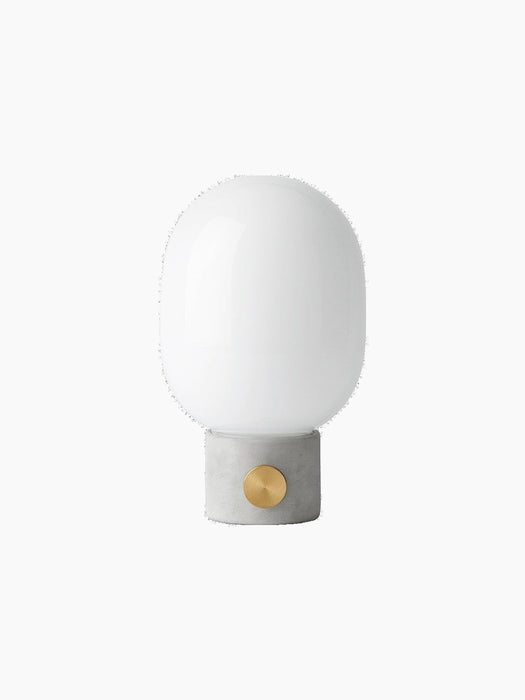 Front view of the JWDA Table Lamp in light grey concrete, with a brass dimmer knob and a rounded white opal glass shade.