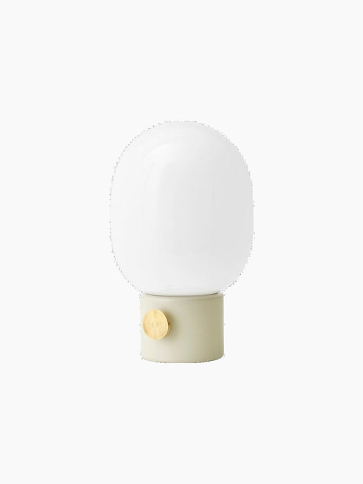 Angled view of the JWDA Table Lamp, Small, in Alabaster White steel with a brass dimmer and a rounded opal glass shade.