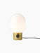 Front view of the JWDA Table Lamp, Small, with a polished brass base and glowing opal glass shade against a black background.
