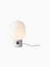 A lit JWDA Table Lamp, Large with a white Carrara marble base, black dimmer switch, and glowing opal glass shade.