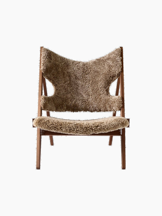 Front view of the Knitting Lounge Chair. The chair has a dark walnut frame and is upholstered in brown sheepskin.