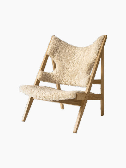 An angled view of the Knitting Lounge Chair, featuring a natural oak frame and upholstered in fluffy Nature sheepskin.