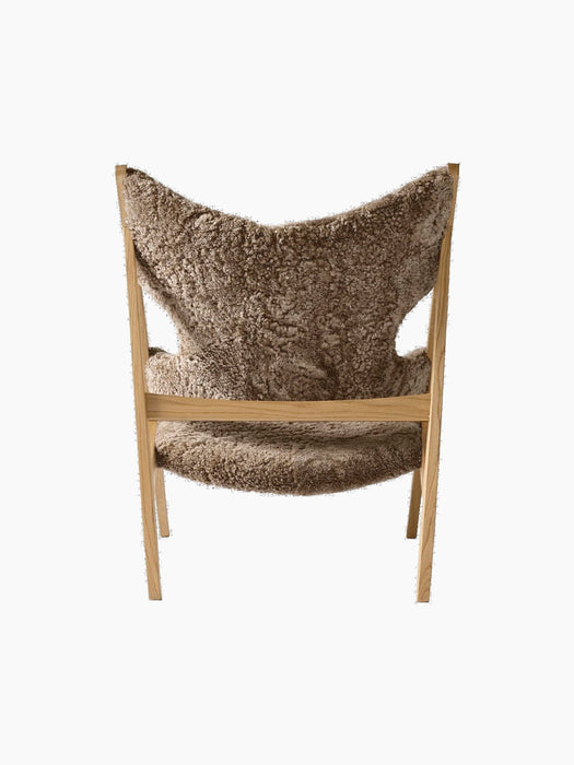 Back view of the Knitting Lounge Chair, showcasing its light brown Sahara sheepskin upholstery and natural oak wooden frame.