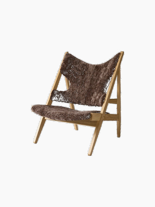 Angled view of the Knitting Lounge Chair. The A-frame is natural oak and the seat is upholstered in dark brown sheepskin.
