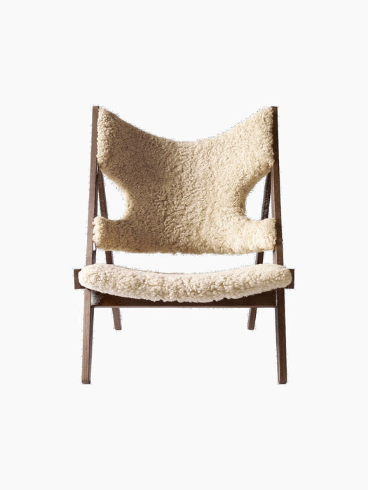 Front view of the Knitting Lounge Chair in natural sheepskin, with a dark stained oak frame against a black background.