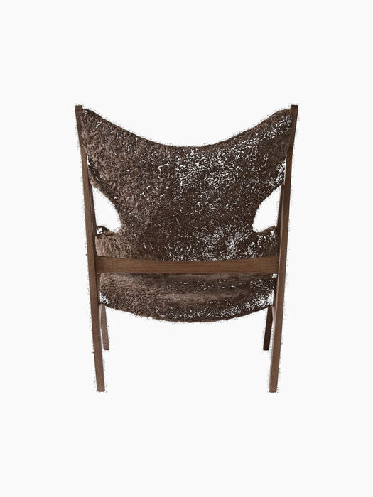 Rear view of the Knitting Lounge Chair, in dark brown sheepskin with a dark stained oak frame and distinctive cutouts.
