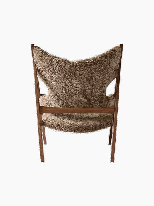 Back view of the Knitting Lounge Chair with a walnut frame and light brown sheepskin upholstery against a black background.