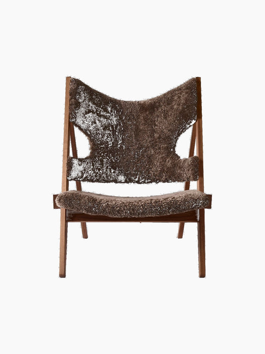 Front view of the Audo CPH Knitting Lounge Chair, featuring plush, dark brown 'Root' sheepskin upholstery on a walnut frame.