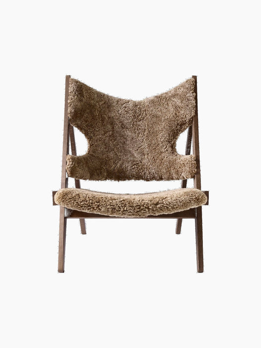 A front-on view of the Knitting Lounge Chair. The chair has a dark stained oak frame and light brown Sahara sheepskin seat.
