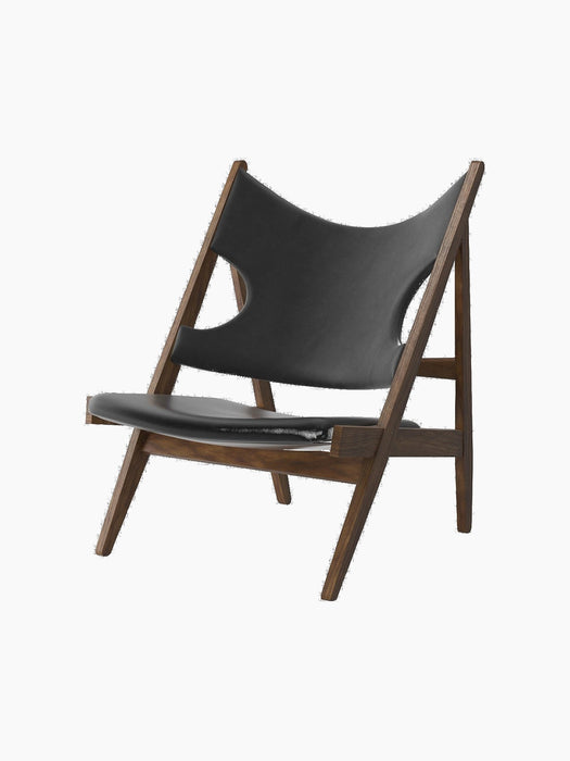 The Knitting Lounge Chair, shown at an angle, features a dark walnut frame and black Dakar leather seat with elbow cut-outs.
