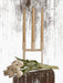 A white Kubus 4 candle holder with three cream candles on a dark wood surface with white tulips against a dark wood wall.