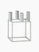The Kubus 4 candle holder in textured zinc finish. It features a geometric, cube-shaped frame with four cylindrical holders.