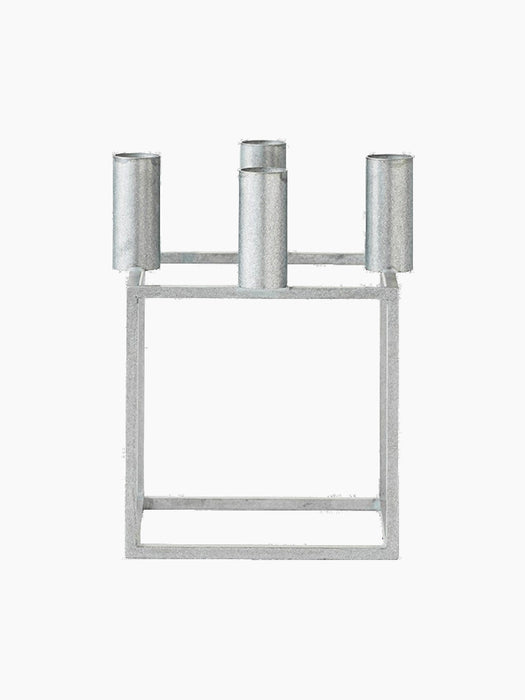 Front view of the Kubus 4 candle holder, with its square frame and four cylindrical sockets in a textured zinc finish.