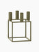 The Kubus 4 candle holder in olive green, shown at an angle. It has a geometric, square metal frame and four candle holders.