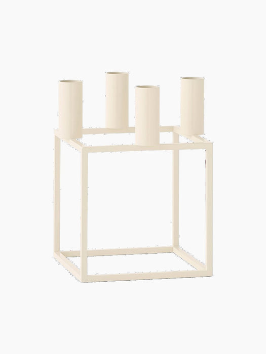 An ivory-coloured Kubus 4 candle holder with a geometric, square frame and four candle sockets, shown from an angle.