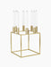 A gold-plated Kubus 8 candle holder with a square frame, holding eight unlit white candles, shown from an angle.
